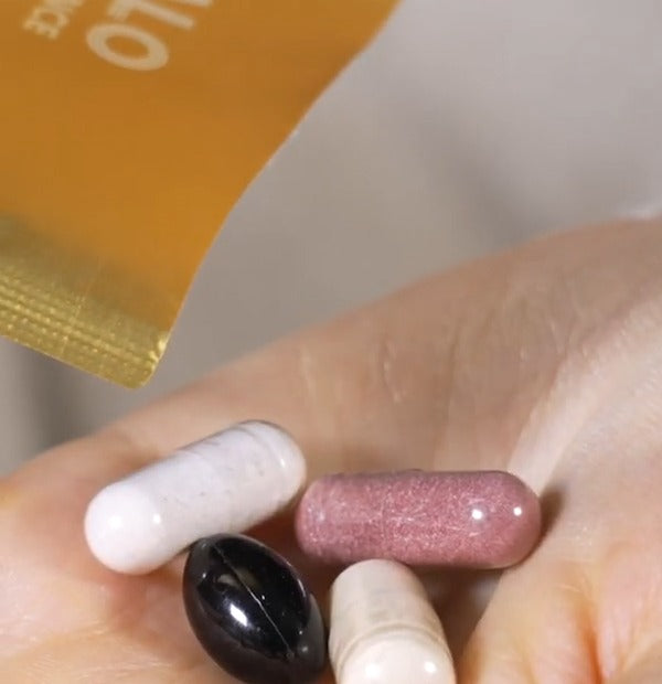 A daily handful of softgels and capsules in an open palm